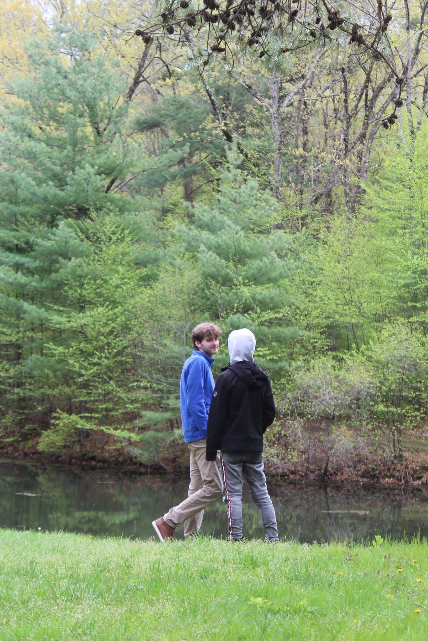 A personal photo outdoors near a wooded pond